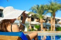 Woman in big white hat lying on a lounger near the swimming pool at the hotel, concept summer time to travel in Egypt Royalty Free Stock Photo