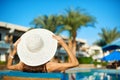 Woman in big white hat lying on a lounger near the swimming pool at the hotel, concept summer time to travel Royalty Free Stock Photo