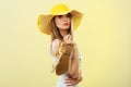 Woman in big yellow summer hat holds sandals Royalty Free Stock Photo