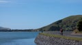 A woman biker cycling along water in Otago Peninsula near Dunedin in the South Island in New Zealand