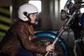 Woman a biker looking in headlight of motorcycle and holding hands wheel, underground garrage