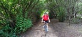 Woman biking in a forest with green trees