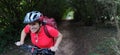 Woman biking in a forest with green trees