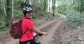 Woman biking in a forest with green trees