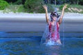 Woman with bikini crimson and hat play water on beach Royalty Free Stock Photo