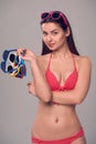 Woman in bikini holding many colourful sunglasses