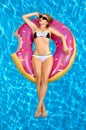 Woman in bikini on the inflatable mattress in the swimming pool.