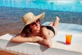 Woman relaxing in hotel swimming pool lying on chaise-longue with cocktail. Summer vacation. All inclusive