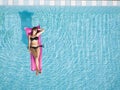 Woman in bikini relaxing on inflatable mattress in the swimming pool of hotel, beach vacation