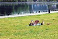 Woman in bikini sunbathing by the pond, lying on grass, reading paper book Royalty Free Stock Photo