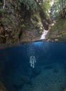 Woman in a bikini swimming underwater in a waterfall with crystal clear water. Royalty Free Stock Photo