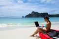Woman in bikini using laptop at the beach