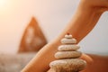 Woman bilds stones pyramid on seashore on a sunny day on the blue sea background. Happy holidays. Pebble beach, calm sea