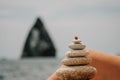 Woman bilds stones pyramid on seashore on a sunny day on the blue sea background. Happy holidays. Pebble beach, calm sea