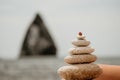 Woman bilds stones pyramid on seashore on a sunny day on the blue sea background. Happy holidays. Pebble beach, calm sea