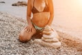 Woman bilds stones pyramid on seashore on a sunny day on the blue sea background. Happy holidays. Pebble beach, calm sea Royalty Free Stock Photo