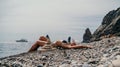 Woman bilds stones pyramid on seashore on a sunny day on the blue sea background. Happy holidays. Pebble beach, calm sea