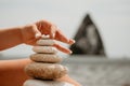 Woman bilds stones pyramid on seashore on a sunny day on the blue sea background. Happy holidays. Pebble beach, calm sea Royalty Free Stock Photo