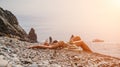 Woman bilds stones pyramid on seashore on a sunny day on the blue sea background. Happy holidays. Pebble beach, calm sea