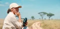 Woman with binoculars enjoying a beautiful view of the African savannah during a safari tour in Tanzania and Kenya