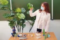 Woman biologist in medical mask with green plant in hand. Problem education in the school during a pandemic coronavirus