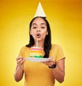 Woman, birthday cake and celebration, blow out candle with rainbow dessert isolated on yellow background. Celebrate