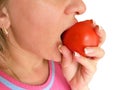 Woman bites and eats tomato closeup image. Part of face with mouth and lips. Red vegetable is in fingers with clear nails.