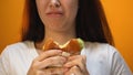 Woman biting unappetizing hamburger, dissatisfied with food quality, closeup