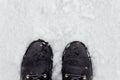 A woman in black boots stands on the snow in winter. Legs close up Royalty Free Stock Photo