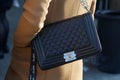 Woman with black Chanel leather bag with silver chain and beige coat before MSGM fashion show, Milan Fashion