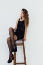 a woman in black clothes and black tights sits posing on a chair Royalty Free Stock Photo