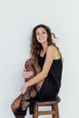 a woman in black clothes and black tights sits posing on a chair Royalty Free Stock Photo