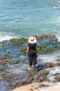 The woman in black clothes and hat standing on the rocks of beach Royalty Free Stock Photo