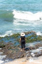 The woman in black clothes and hat standing on the rocks of beach Royalty Free Stock Photo