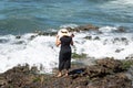 The woman in black clothes and hat standing on the rocks of beach Royalty Free Stock Photo