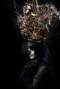 Woman in black clothes and skull makeup, a crown of dry branches and flowers on her head