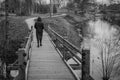 Woman in black coat crosses wooden bridge, depressed view Royalty Free Stock Photo