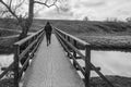 Woman in black coat crosses wooden bridge, depressed view Royalty Free Stock Photo