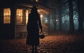 a woman in a black coat and hat is standing in front of a house in the woods at night Royalty Free Stock Photo