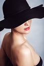 Woman in black dress and hat with bare shoulders