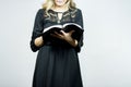 Woman with a black dress reading the bible under the lights against a white background