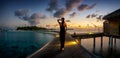 A woman in a black dress walks down a pier towards a tropical island in the Maldives Royalty Free Stock Photo
