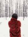 Woman with black hair from behind standing in snowy forest during winter, wearing a red fur coat Royalty Free Stock Photo