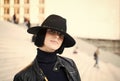 Woman in black hat and jacket pose on stairs