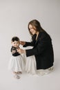 a woman in a black jacket is sitting next to a little girl in a white dress Royalty Free Stock Photo