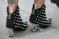 Woman with black Laura Biagiotti shoes with silver studs and heel before Emporio Armani fashion