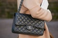 Woman with black leather Chanel bag and beige jacket before Salvatore Ferragamo fashion show,