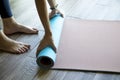 A woman in black leggings has finished or is starting a workout, rolling a sports mat, cropped image. The concept of