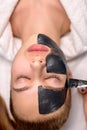 Woman with black mask on face close-up, top view. Spa treatments, beauty concept Royalty Free Stock Photo