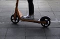 Woman in black pants and white sneakers rides an electric scooter